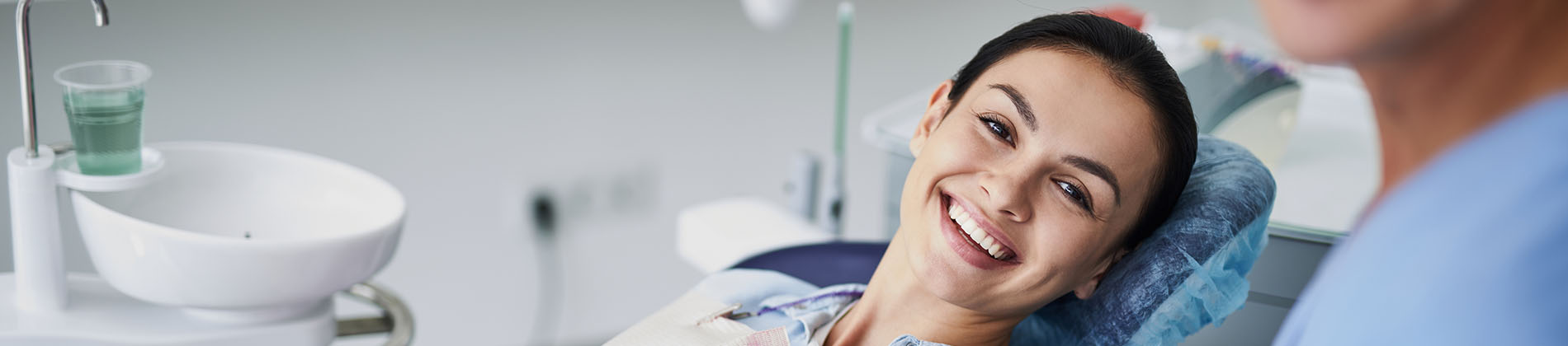 A well-lit reception area with a desk, computer monitor, and potted plant.